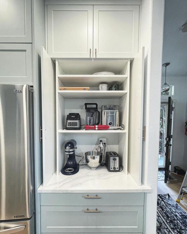 White shaker coffee station from @braveelement. Built-in shelves hold small appliances beside a marble-look counter.