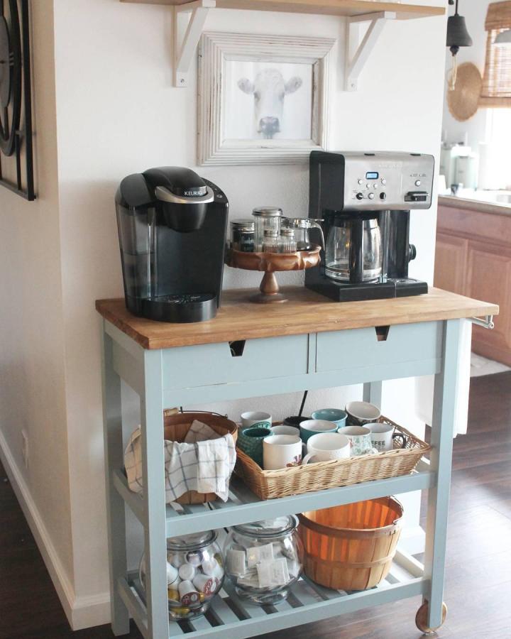 Pale blue-gray IKEA coffee cart from @sandrajoanliving. Warm wood top, coffee makers, mugs, and baskets create cozy beverage station.