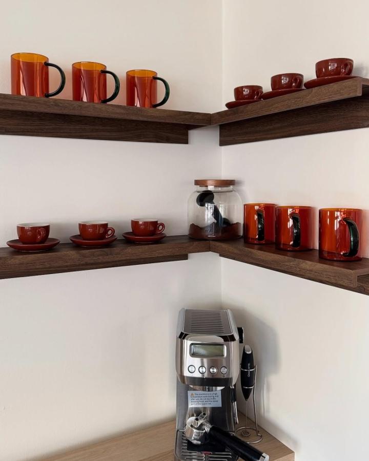 Dark walnut corner coffee station from @torpioconstruction. IKEA MOSSLANDA shelves display amber mugs, red cups, and an espresso machine.