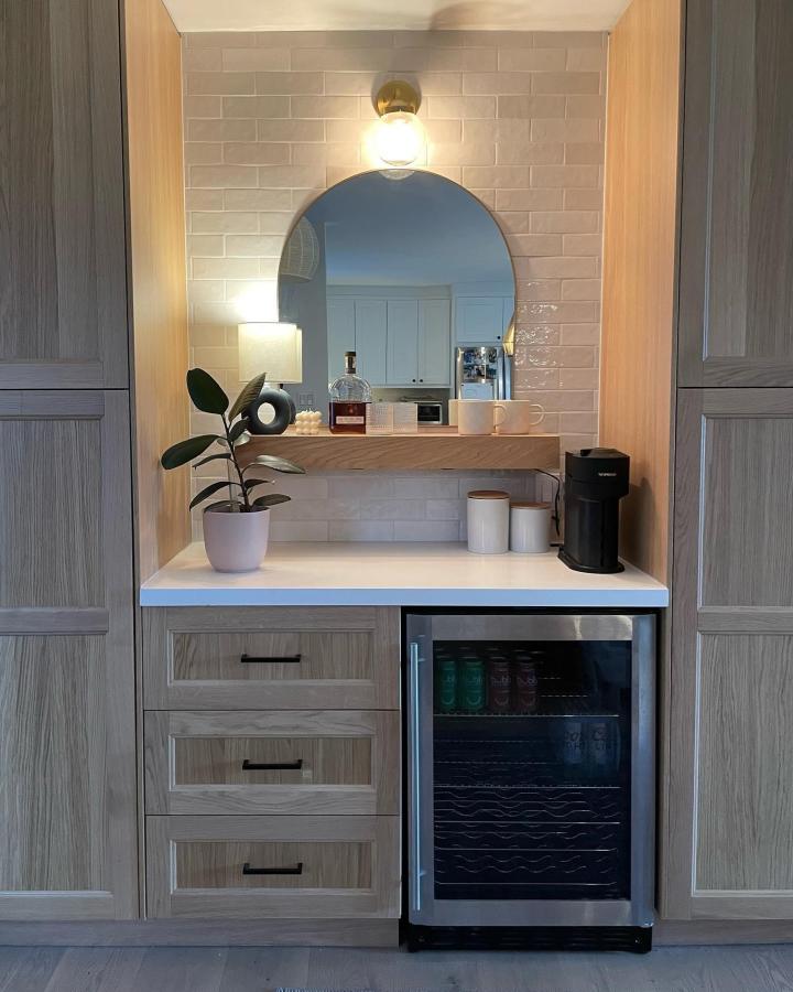 Warm gray IKEA coffee bar from @shentsrenovation. Arched mirror, pale tile backsplash, white counter, and compact beverage fridge.