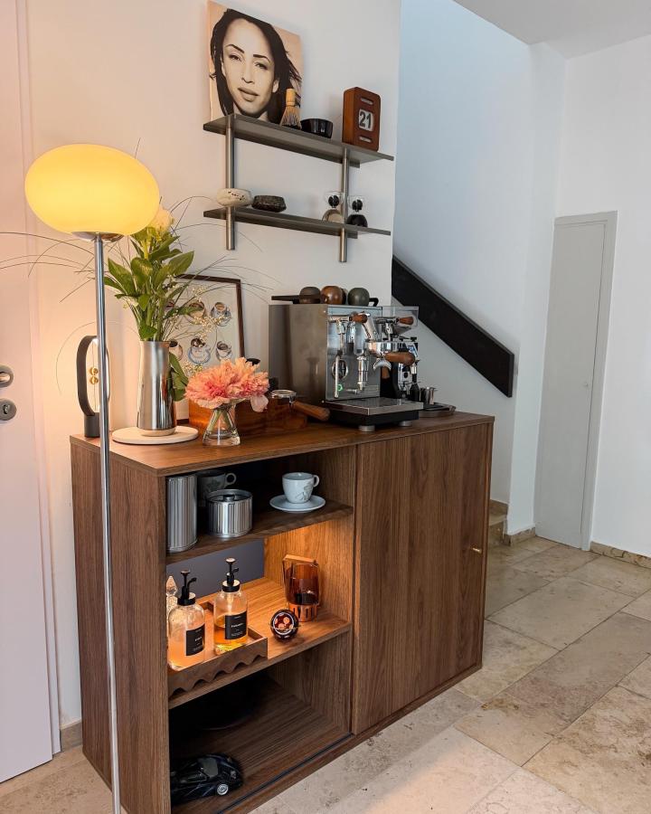 Warm walnut coffee station from @profitecespresso. Wall shelves, espresso machine, flowers, and open storage.