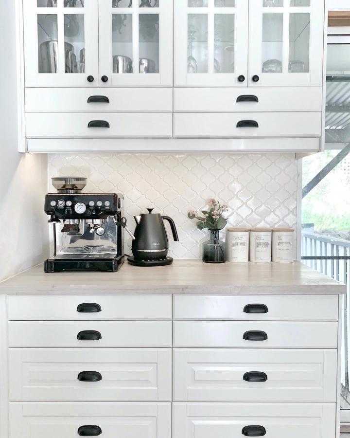 White BODBYN glass-door coffee bar from @marikaknowsthings. Styled for ikea coffee bar hacks ideas with black handles.