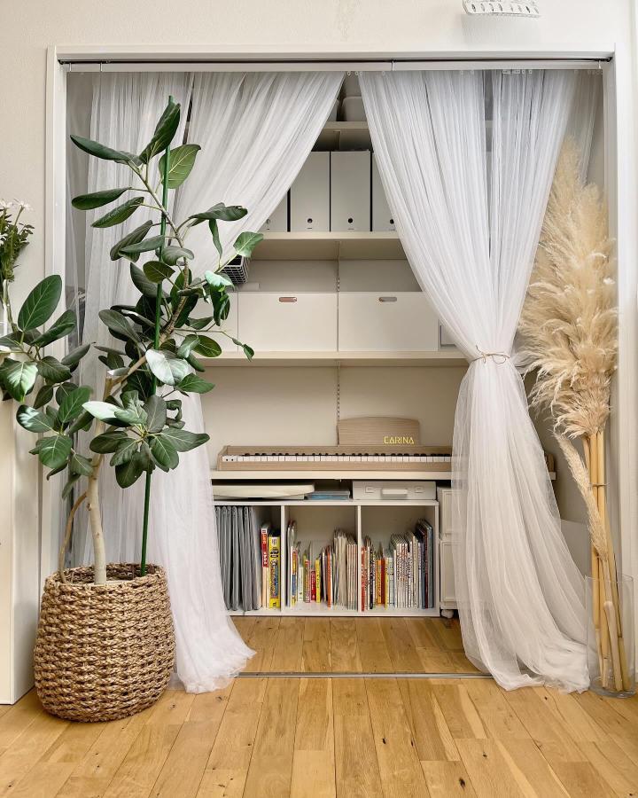 White sheer curtain room divider from @na_chan.home. Softly frames a piano nook and organized storage.