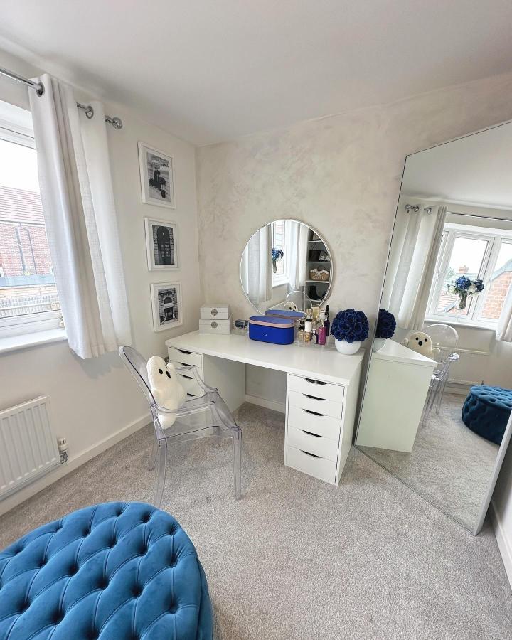 White minimalist dressing table from @athomewithkirsty_. Round mirror, blue accents, and clear chair