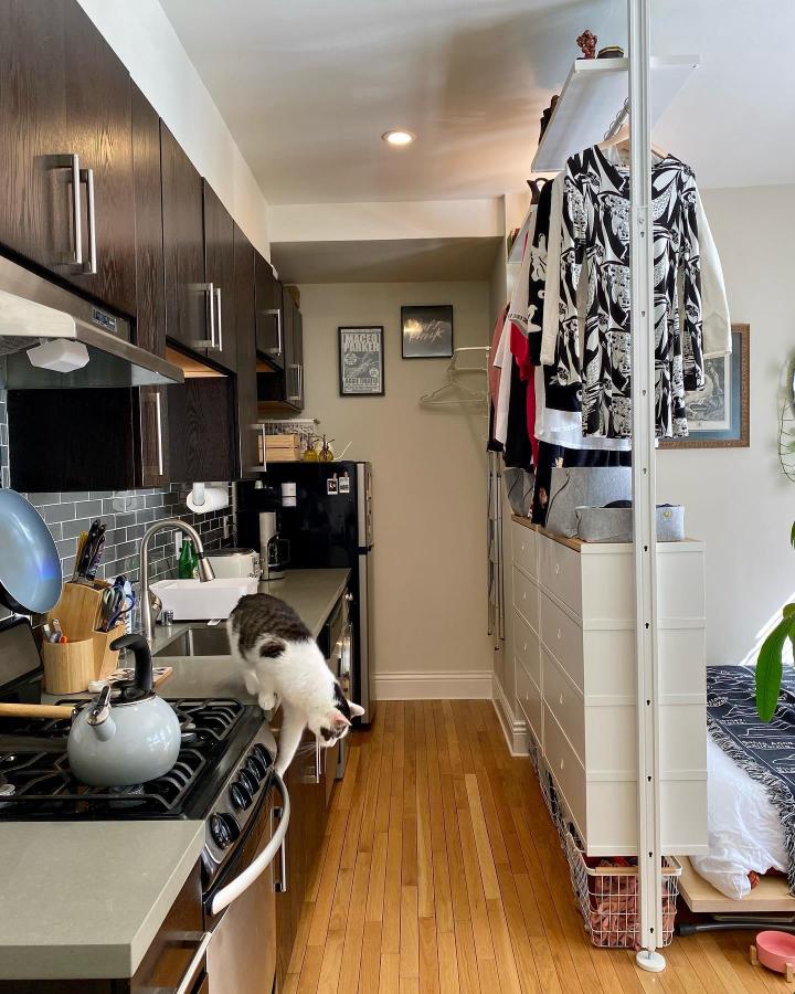 White open-frame kitchen divider from @k.astraelis. Elvarli shelving separates the cooking area from a bedroom nook.