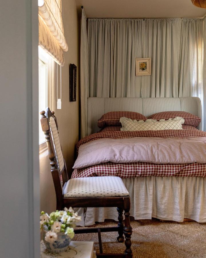 Pale sage striped bedroom headboard from @ashtonscottage. Upholstered IKEA makeover with gingham bedding and curtain backdrop.