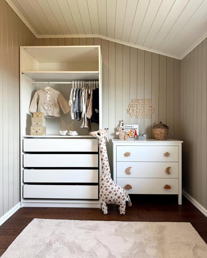 White built-in nursery wardrobe from @homeby_idak. Open shelving, drawers, and hanging rails beside a moon-front dresser.