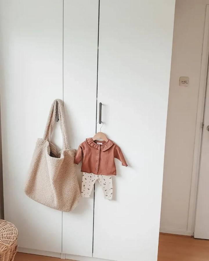 White Ikea PAX wardrobe from @huisje.van.geluk. Calm ikea pax nursery ideas with teddy tote and dusty rose baby outfit.