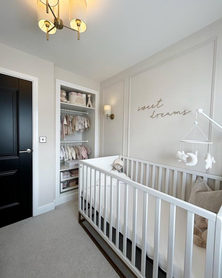 Soft Gray Built-In Nursery Wardrobe from @clarissashome. White PAX shelving, baby clothes, crib, and cloud mobile.
