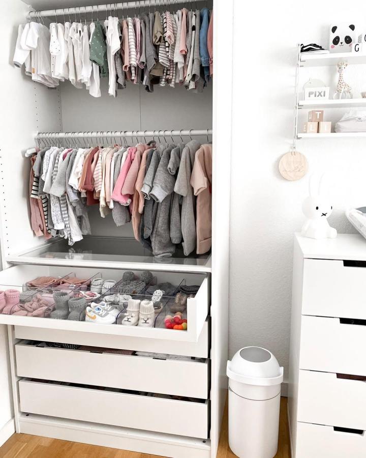 Soft pink and gray PAX nursery wardrobe from @isii_bla. Open rails, drawers, baby clothes, and tiny shoes.