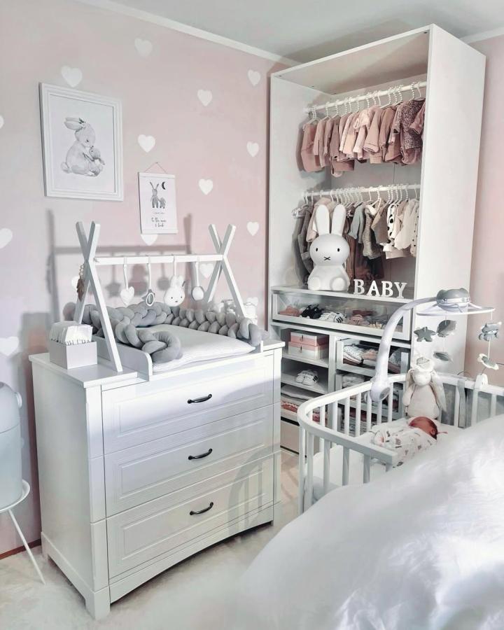 White open wardrobe from @jenna_franke. Blush nursery storage with double rails and tiny clothes.
