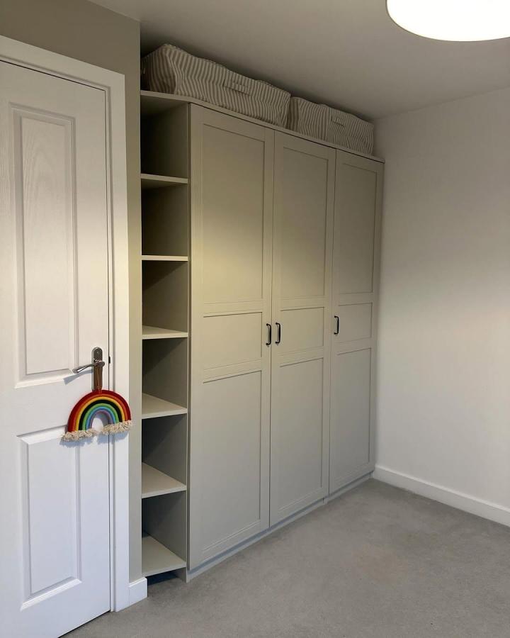 Soft gray shaker IKEA PAX nursery wardrobe from @abilucyhome. Open shelving and striped storage baskets create calm organization.