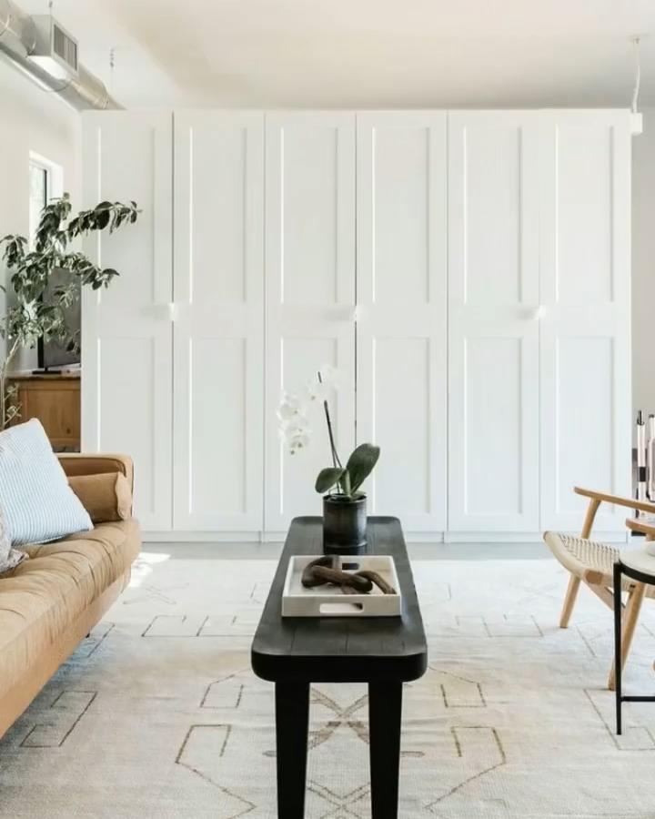 White paneled living room divider from @theinteriorcollective. Custom PAX doors separate the bright seating area.