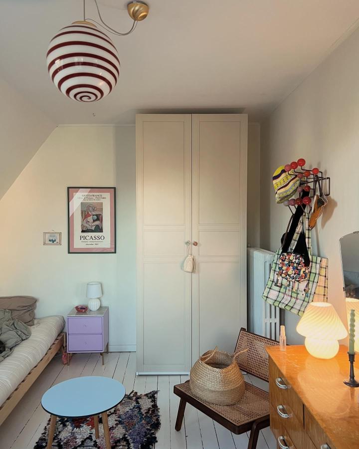 Cream paneled IKEA PAX wardrobe from @_mernee. Cozy attic bedroom with colorful accents and woven storage.