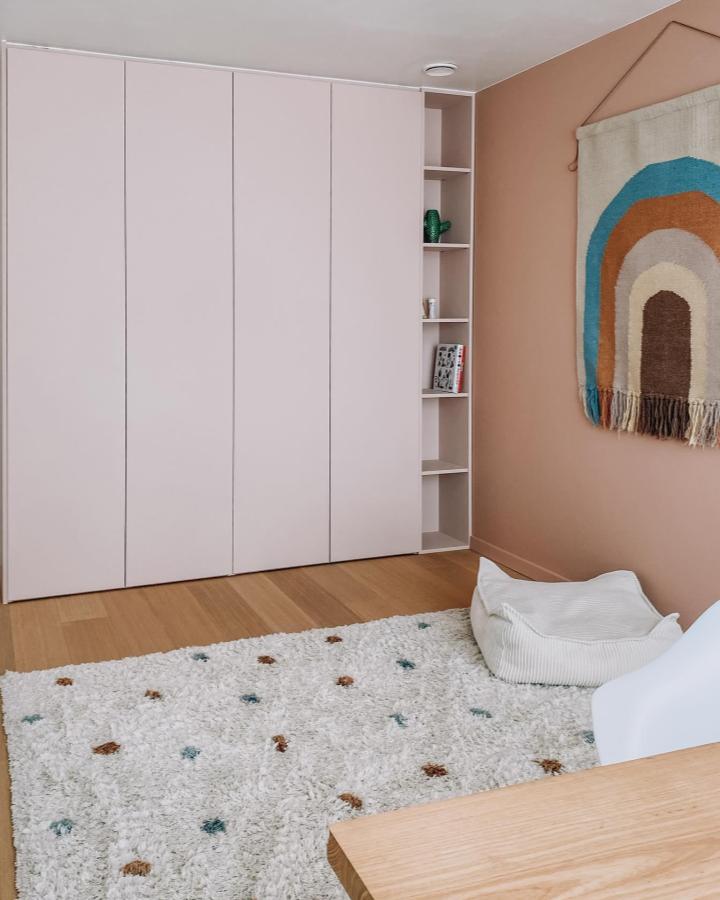 Pale pink minimalist wardrobe from @house.ndl. Built-in PAX storage with open shelving beside a cozy bedroom.