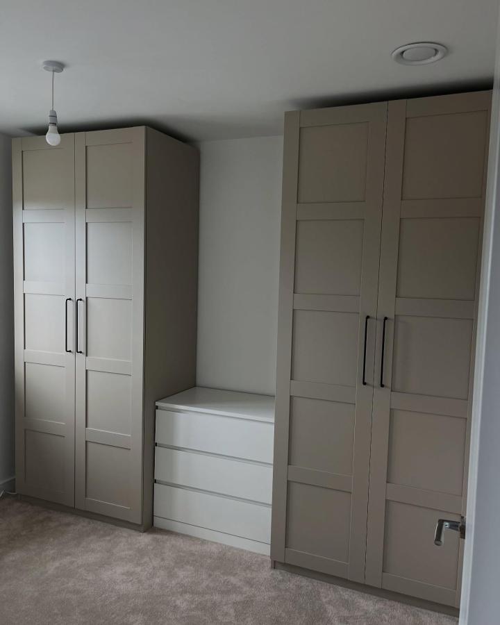Greige IKEA PAX wardrobes from @our.home.no75. White drawers and black handles create fitted small-bedroom storage.