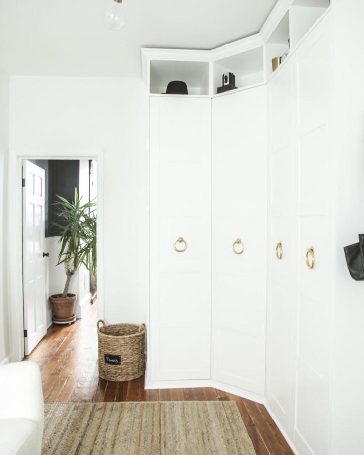 White built-in wardrobe from and christina. Gold ring pulls and open shelving suit compact bedroom storage.