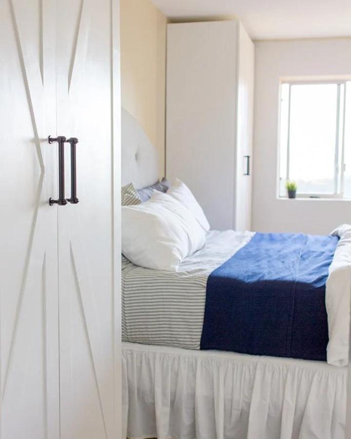 White geometric PAX wardrobe from jenna sue design co.. Slim doors frame a small bedroom.