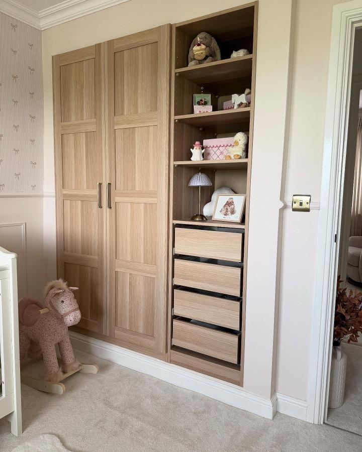 Warm oak paneled Ikea Pax wardrobe from @homebyrosie. Open shelving displays toys and keepsakes beside drawers.