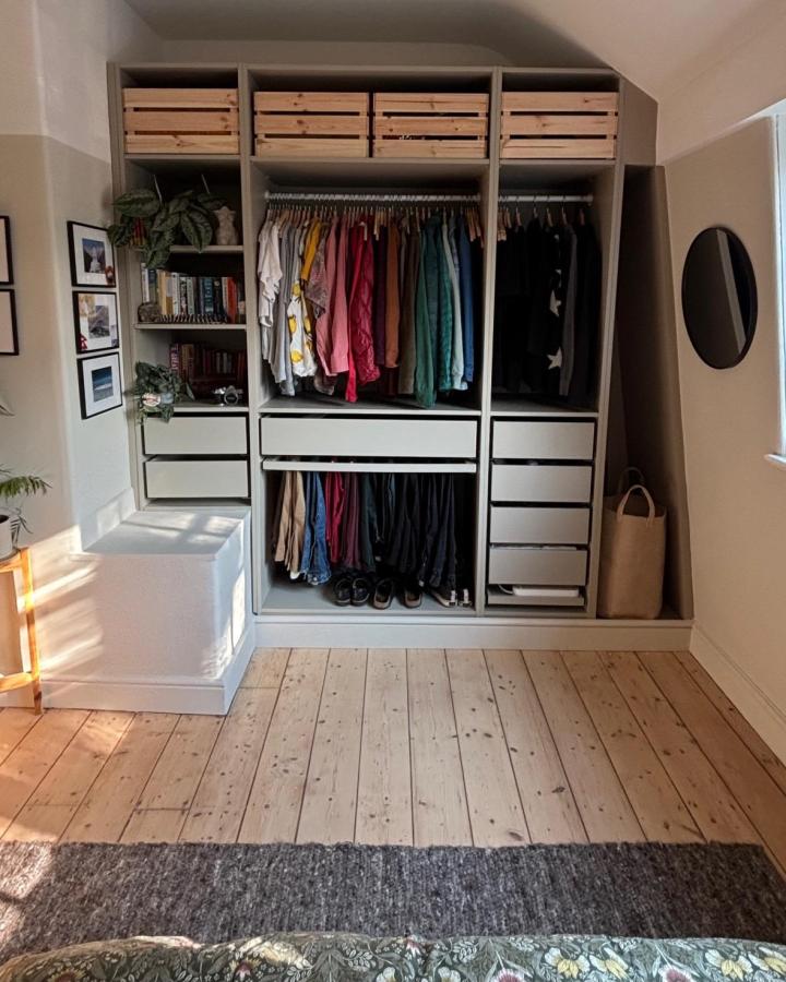 Warm gray open wardrobe from @myportsunlightcottage. Timber crates and colorful clothing maximize a compact bedroom.
