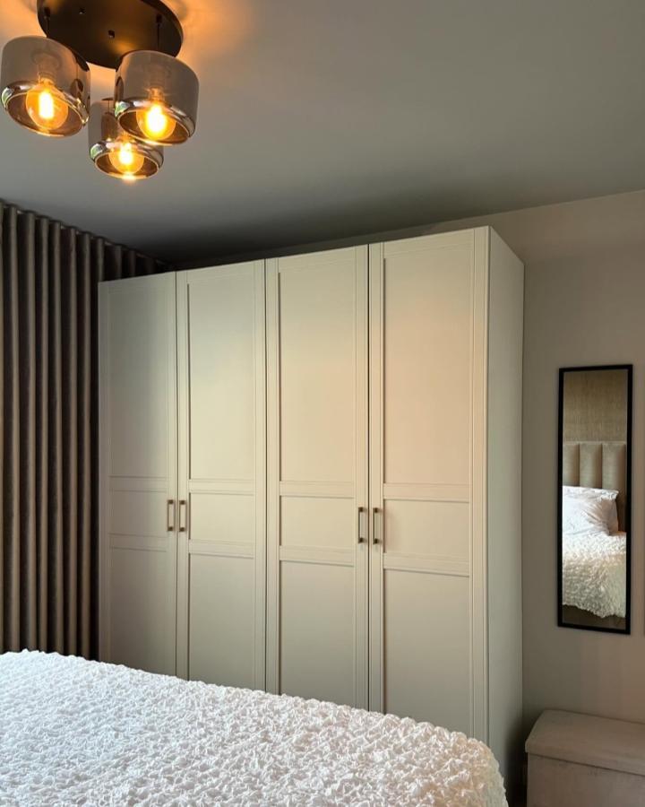 Cream paneled wardrobe from @wijnhuisje. Floor-to-ceiling storage beside a softly lit small bedroom.
