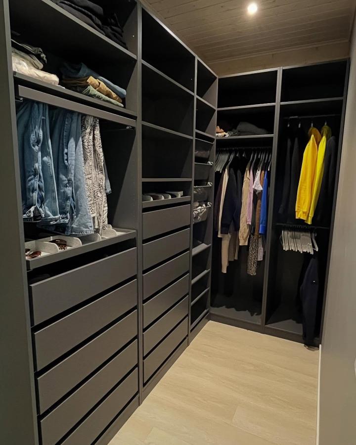 Matte black walk-in closet from @hirsitorpassa. Light oak floor, open shelving, drawers, and bright yellow clothing