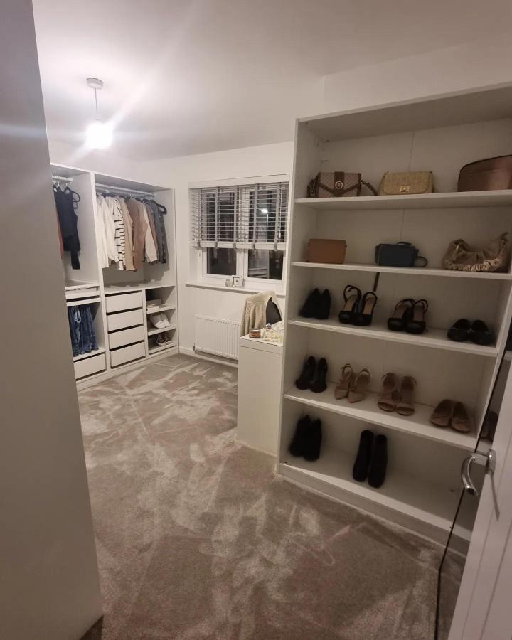 White open-shelf walk-in closet from @chalmershome. Neutral carpet, hanging clothes, handbags, and neatly arranged shoes.