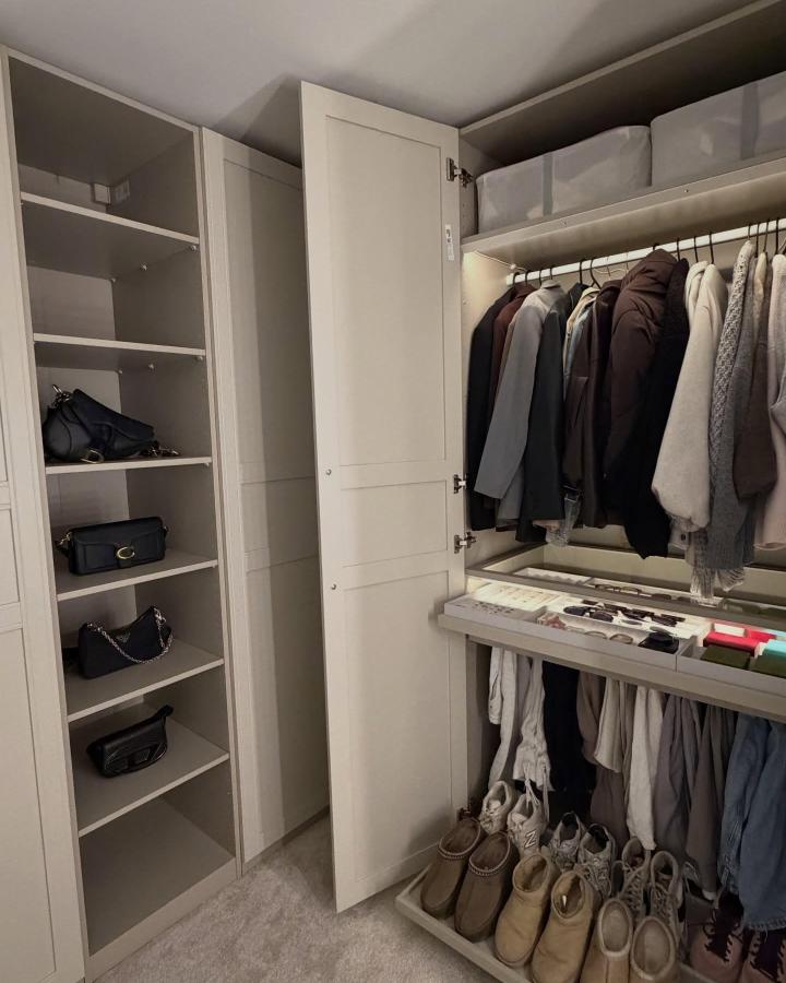 Soft Gray IKEA PAX Walk-In Closet From @homebylivs. Open shelves, concealed door, clothing rails, shoe storage, and warm lighting.
