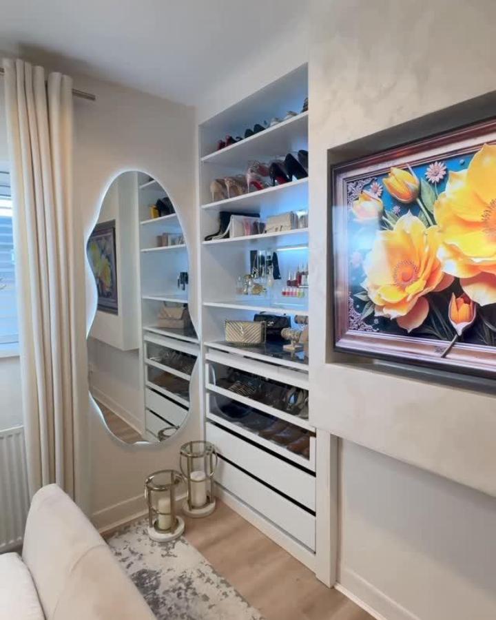 White arched mirror and shelving wardrobe from @inspiredby_el. Built-in dressing nook with shoes, drawers, and floral artwork.