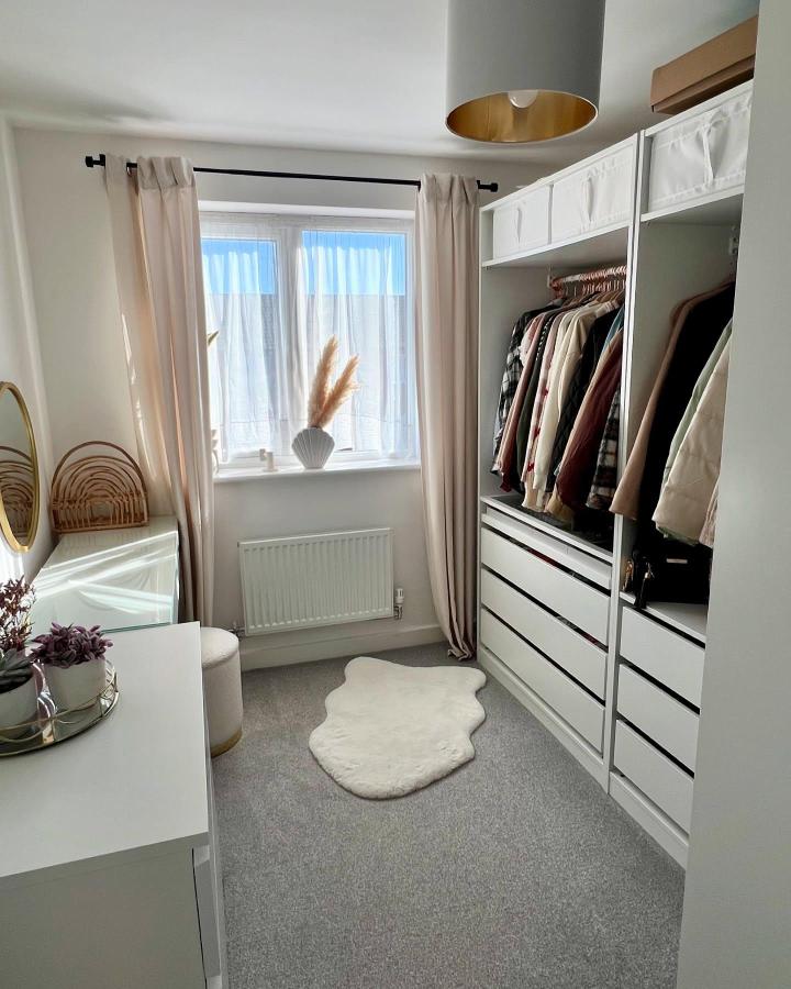 Soft white Ikea Pax walk-in closet from @ewaxalbert_home. Open rails, drawers, blush curtains, and a cozy rug.
