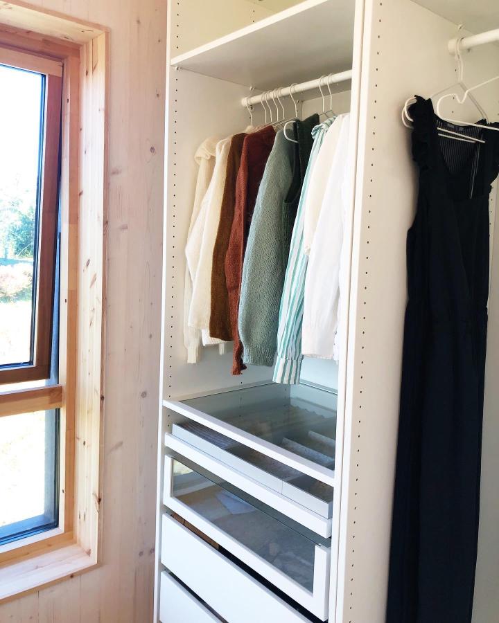 White modular walk-in closet from @brautabo. Glass drawers, open rails, and warm wood trim maximize storage.