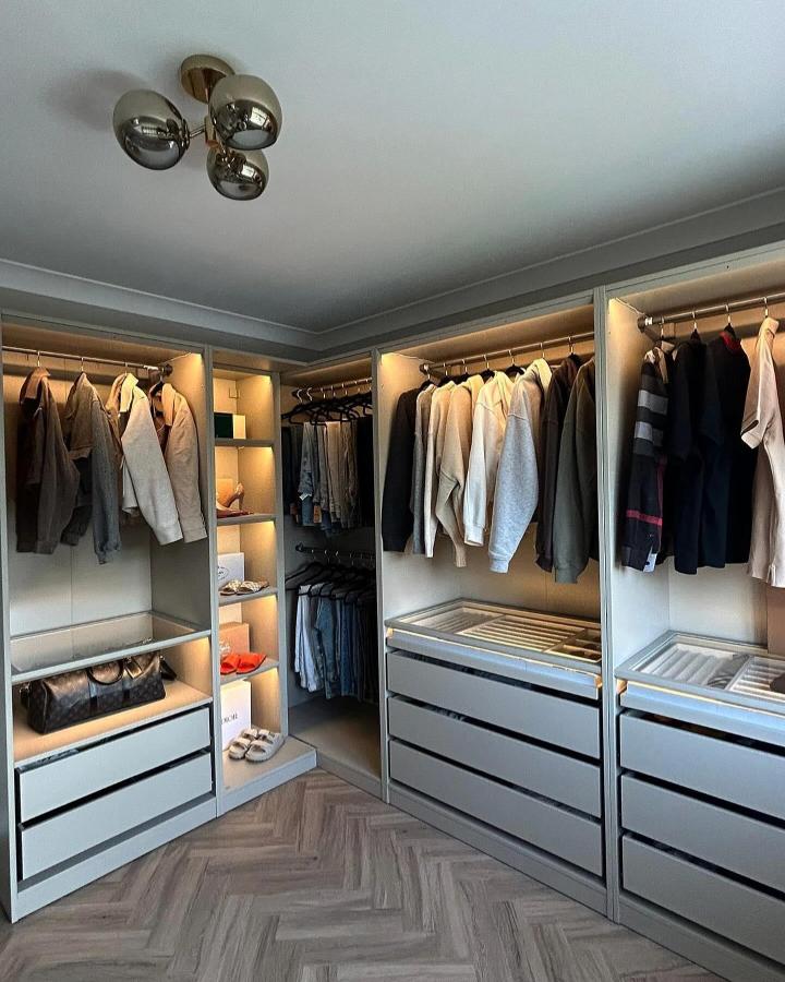 Warm gray built-in closet from @insidenumber48. IKEA PAX dressing room with lit rails, drawers, and herringbone flooring.