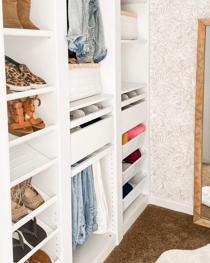 White shelving walk-in closet from @mrsmeganjane. ikea pax walk in closet ideas feature shoes, baskets, denim, and botanical wallpaper.