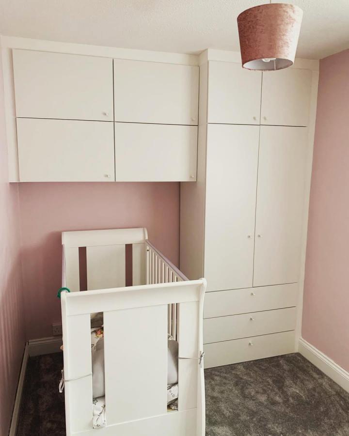 White built-in nursery wardrobe from @thehandycarpenter1. ikea platsa wardrobe ideas feature overhead cabinets and drawers beside a cot.