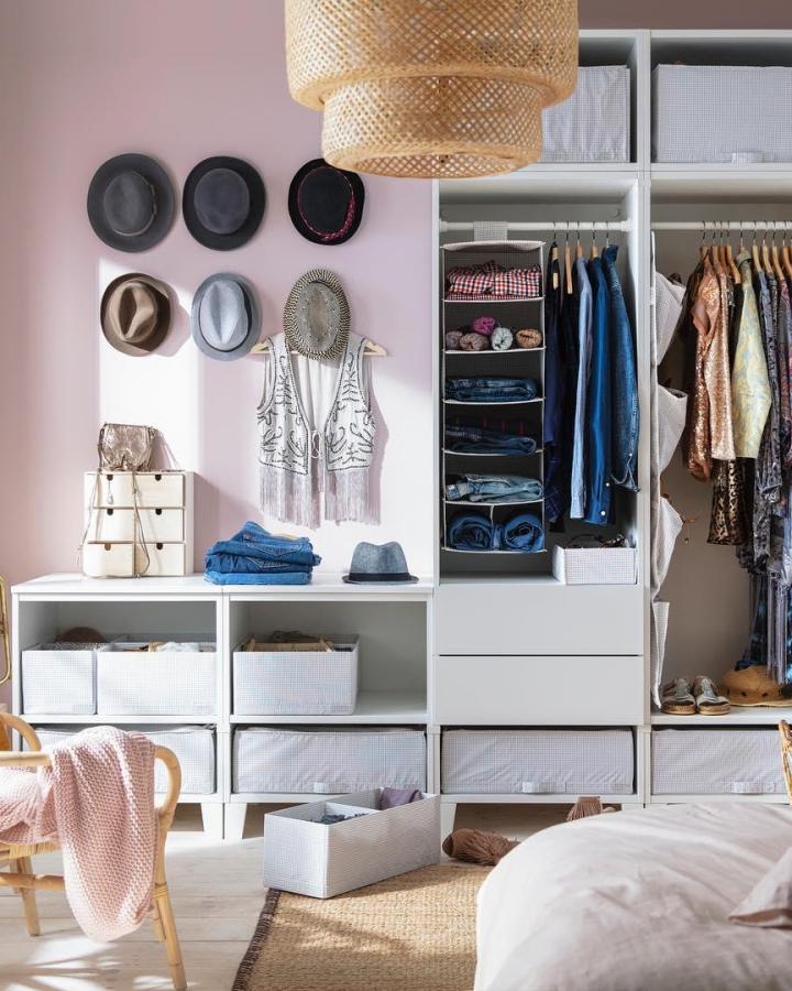 White open modular wardrobe from @ikea_australia. Fabric bins, hanging clothes, hats, and rattan pendant fill a bright bedroom.