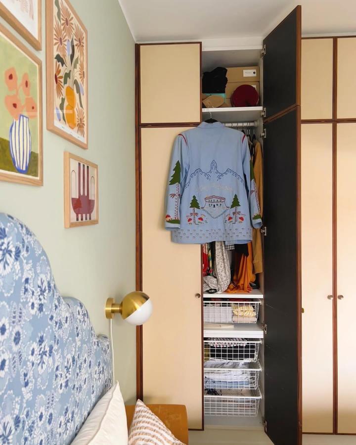 Warm beige and walnut trim bedroom wardrobe from @thusthefuss. Open shelving and wire baskets organize clothing.