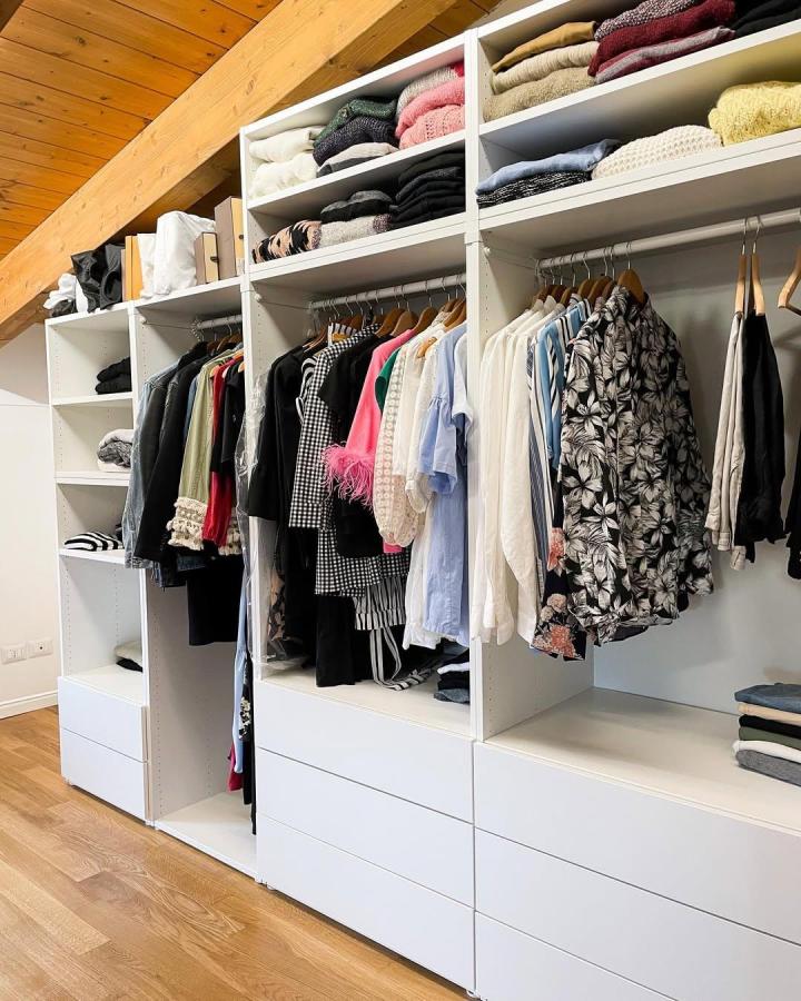 White open wardrobe from @ourwhiteapartment. ikea platsa wardrobe ideas with drawers, rails, and folded knitwear beneath a sloping ceiling.
