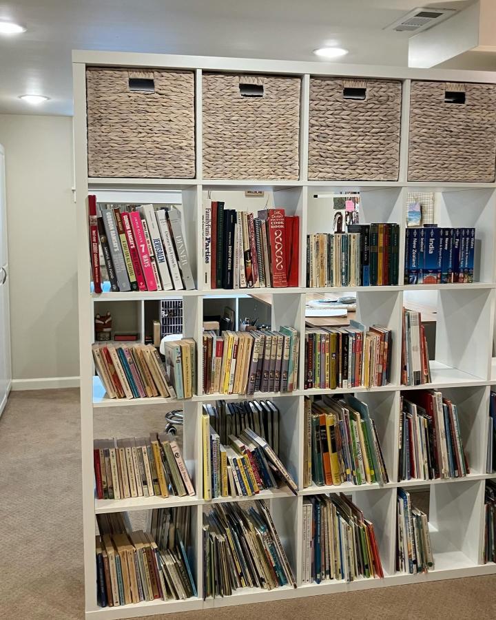 White KALLAX room divider from @findandrefined. Woven baskets and colorful books separate a cozy creative workspace.