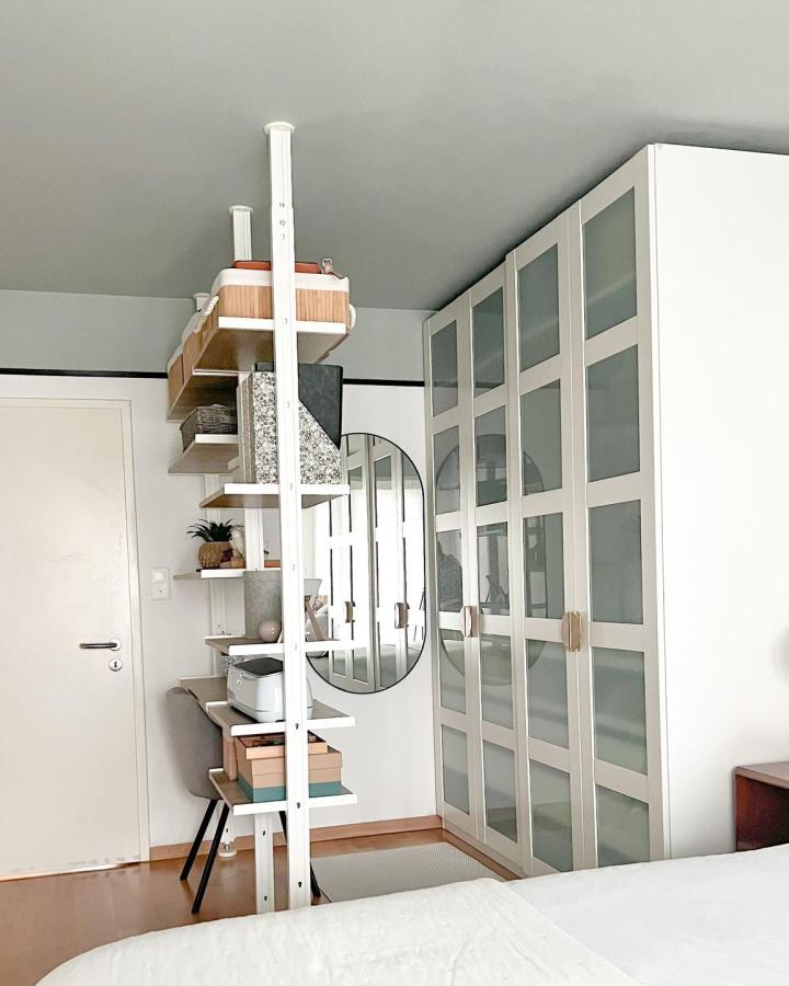 White IKEA wardrobe and shelving from @dkore.ch. Frosted panels divide a compact bedroom and office.