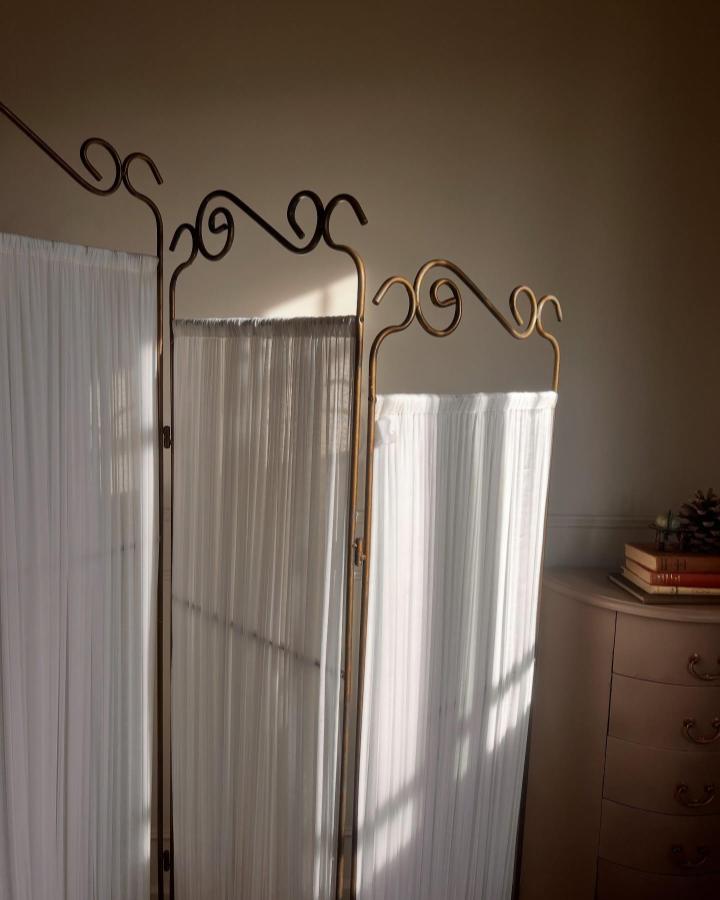 Bronze ornate folding screen from @brwazeen. Sheer white panels softly divide a compact bedroom.