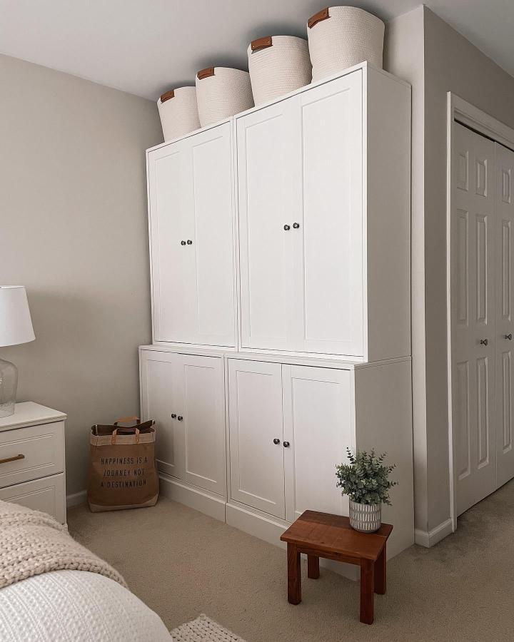 White paneled bedroom storage from @absolutelyairs. Stacked IKEA cabinets maximize a compact room.