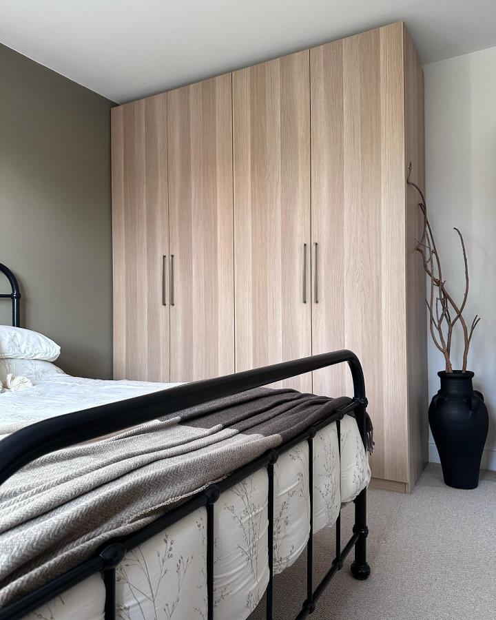Warm oak-effect PAX wardrobe from @fixingupno40. Compact bedroom storage with black handles and a vintage bed frame.