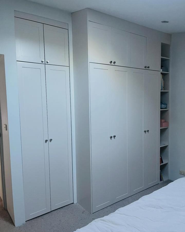 Pale gray IKEA PAX wardrobe wall from @burra_design. Built-in storage with open shelving beside the bed.