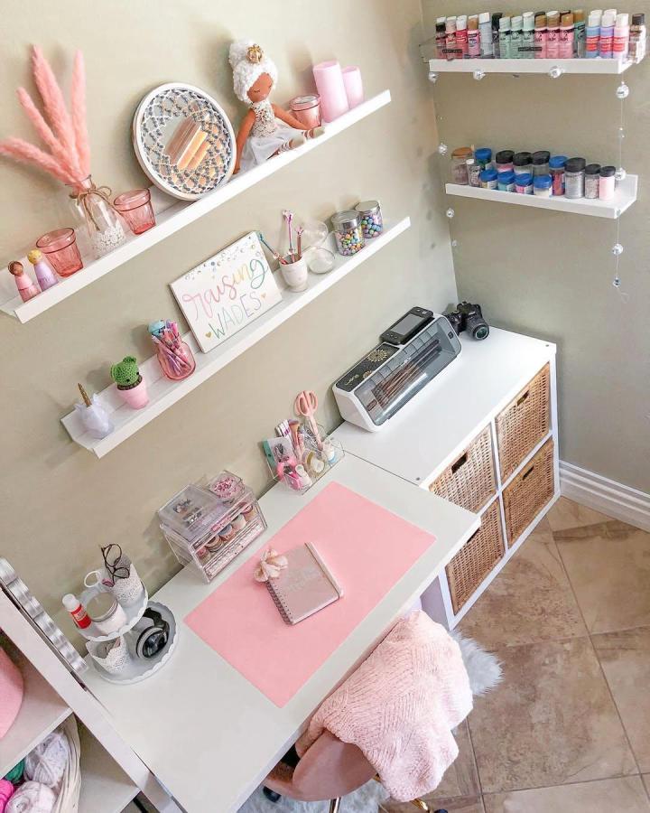 Pink-and-white craft room from @_jenmagic_. Wall ledges, paint bottles, wicker drawers, and compact cutting machine.
