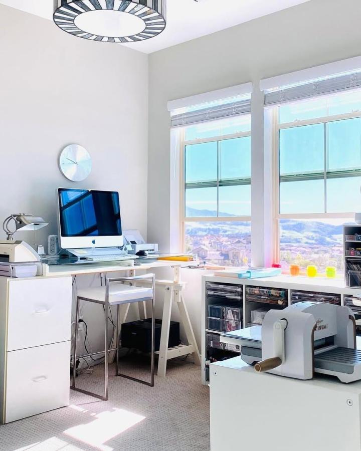 Bright white ikea small craft room ideas workspace from @lisasoares. Windowed desk, cutting machine, and organized drawers.