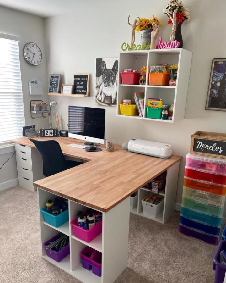 White-and-wood craft workspace from @dan.morelos. Colorful bins organize supplies beneath a compact desk.