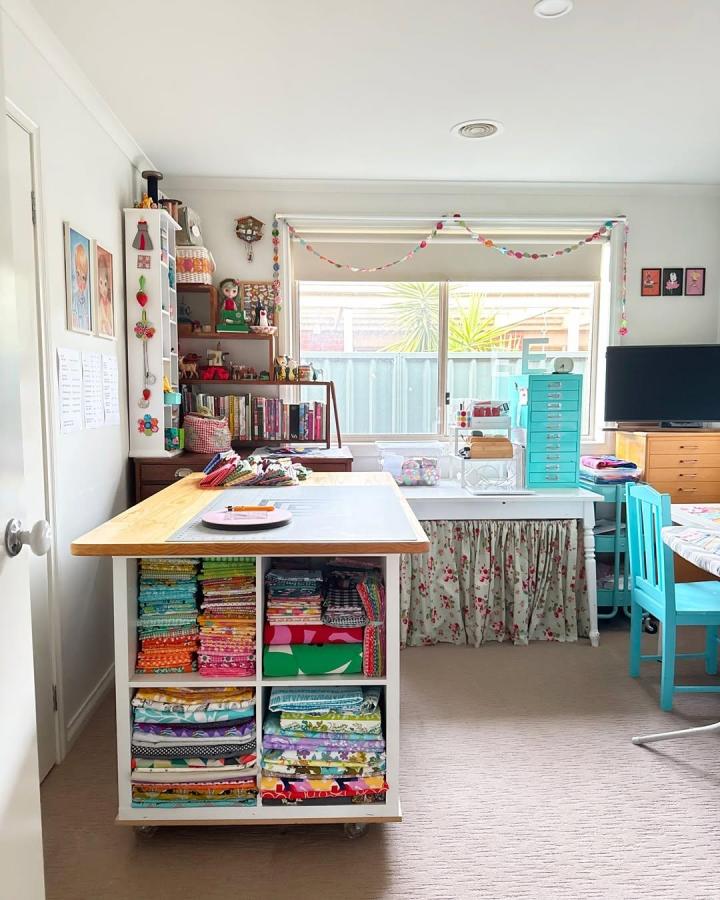 Colorful fabric-filled KALLAX craft island from @emmajeanjansen. Aqua drawers and floral curtains brighten the compact workspace.