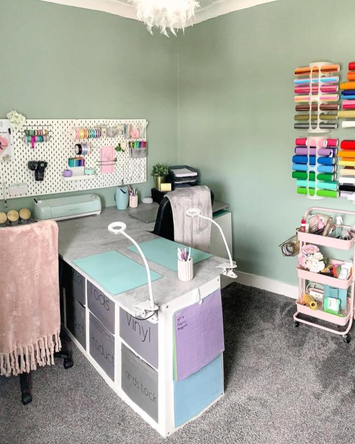 Sage green Ikea craft room from @richardson_house. White pegboard, mint desk, rainbow supplies, and rolling cart maximize storage.