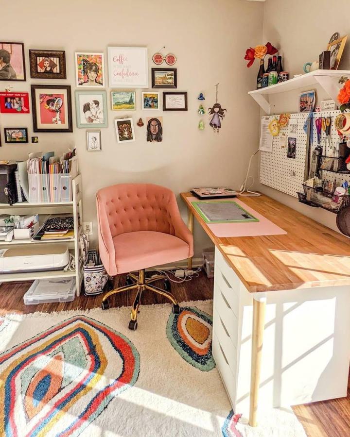 Warm wood and white craft room from @paperandpiece. Blush chair, pegboard, and colorful rug organize a sunny workspace.
