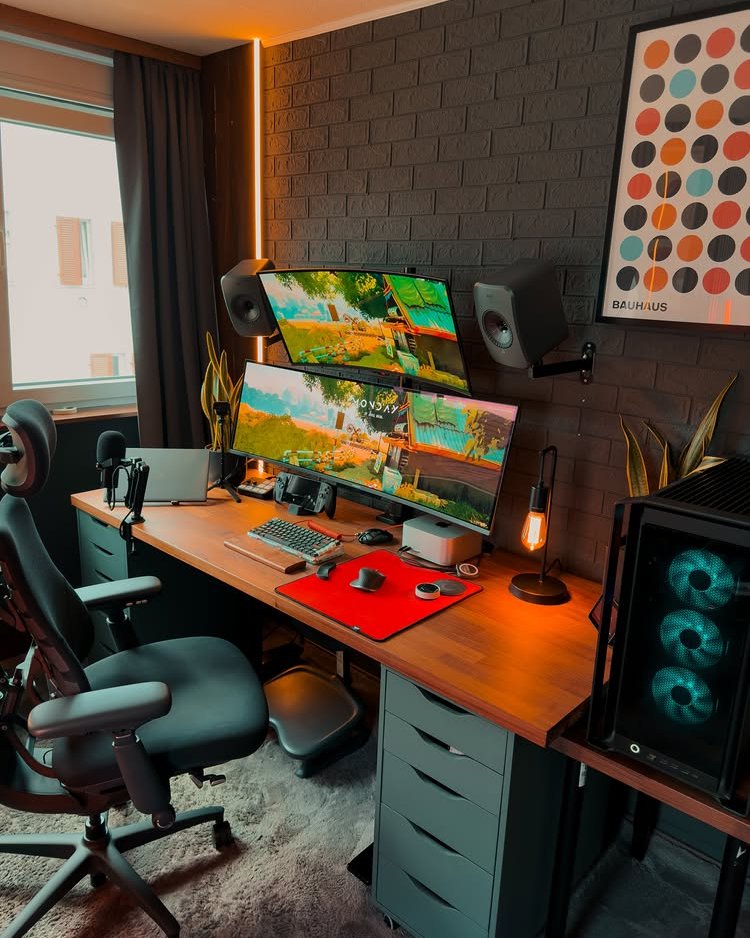 Warm wood IKEA ALEX desk with dual monitors, black drawer units, speakers, and cozy gaming accents